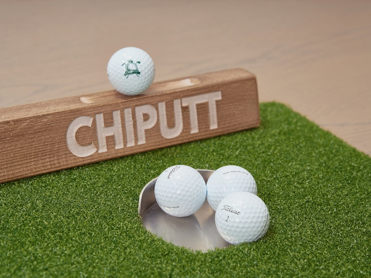 Golf balls on a putting green with wooden marker.