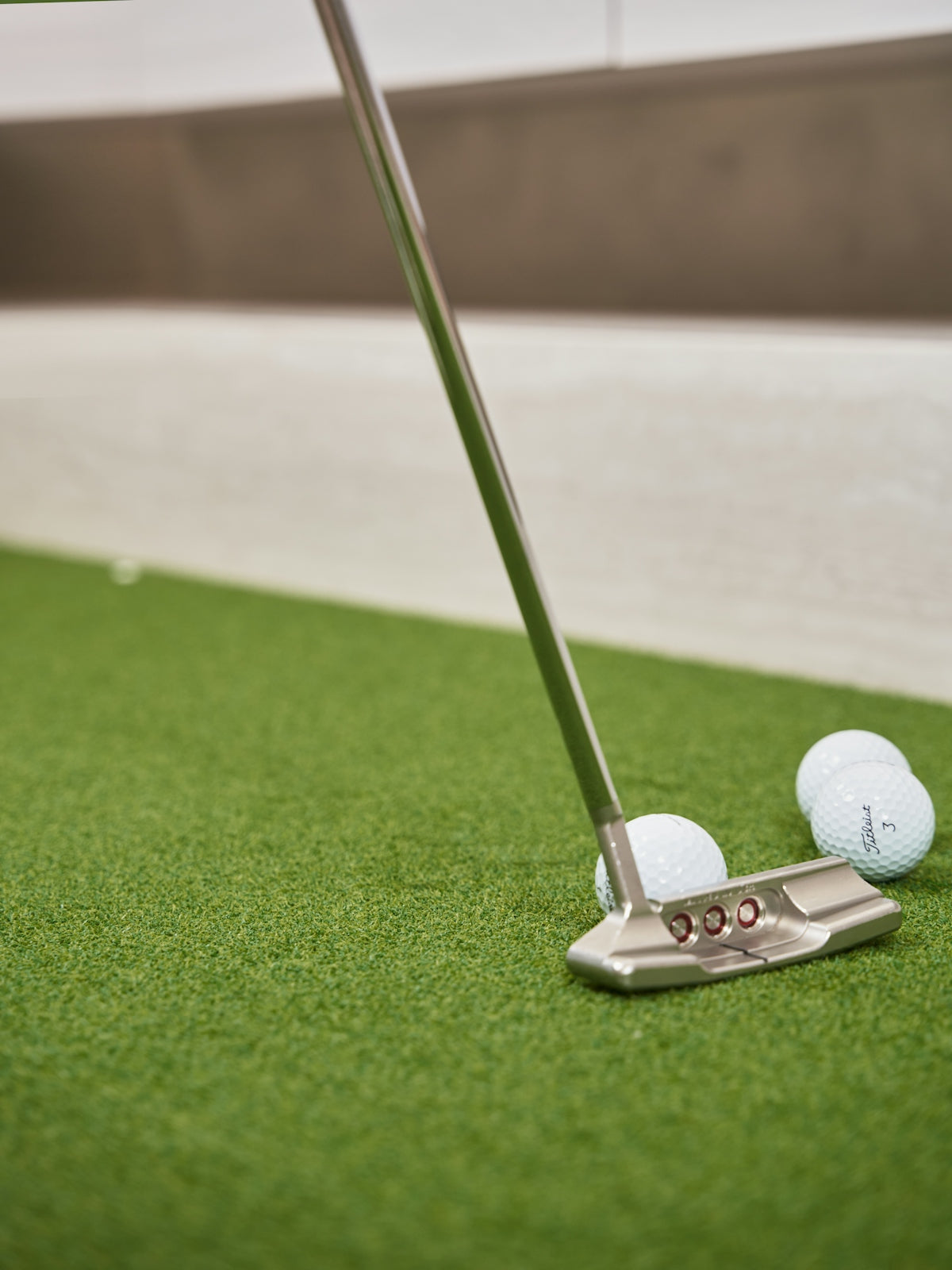 Golf putter and balls on artificial turf.