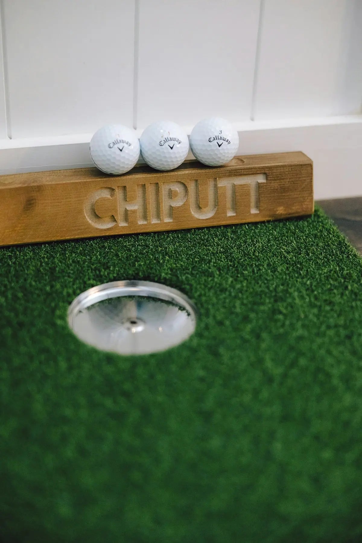Three golf balls on a putting green near hole.