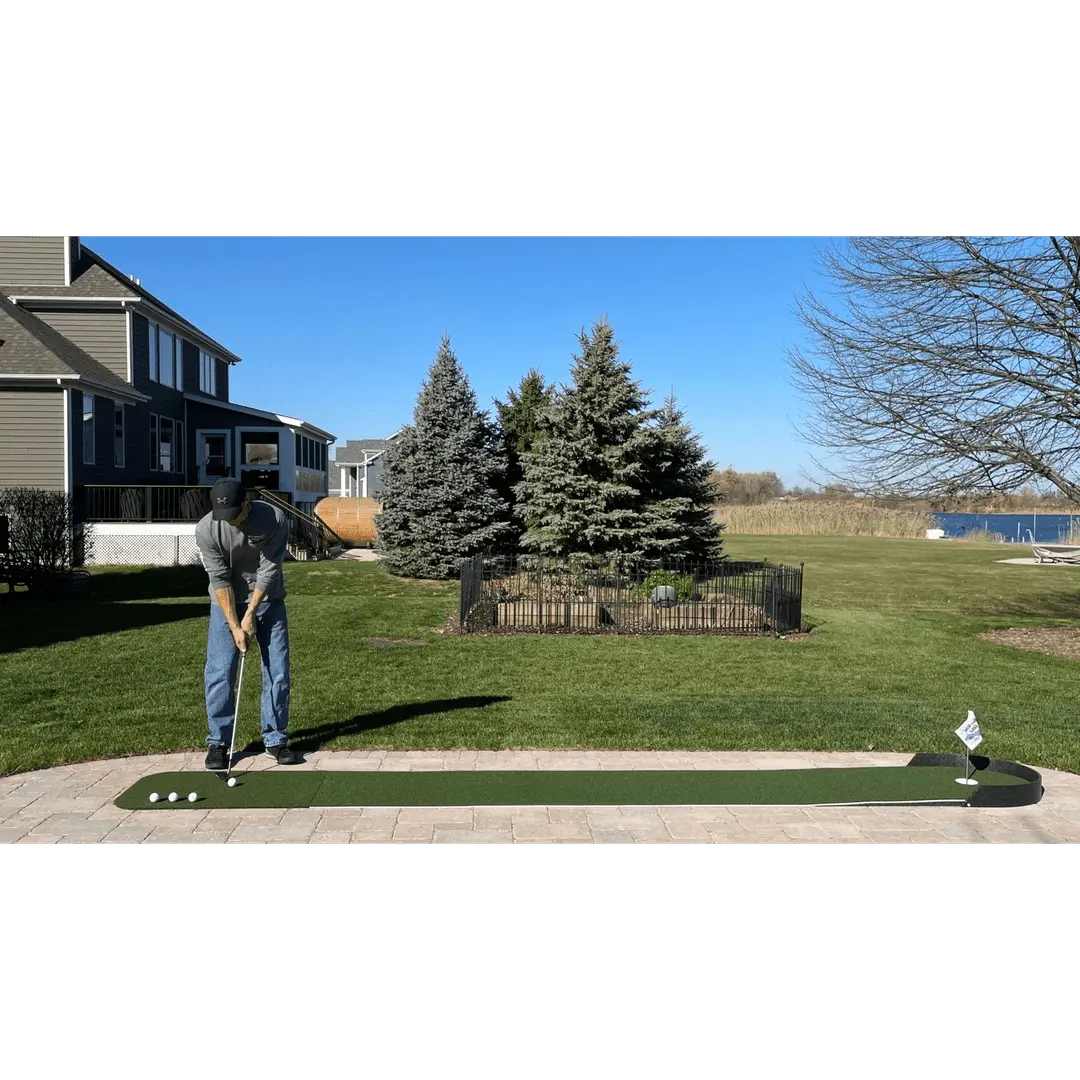 Person putting on Big Moss Commander Patio Series 215 green, with houses and pine trees visible in the background