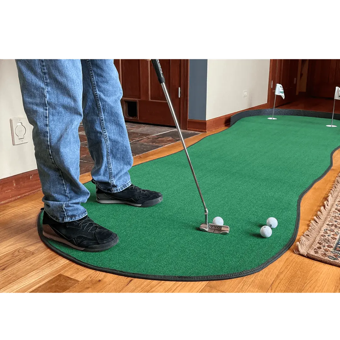 Person in jeans using Big Moss The Augusta 410 Putting Green indoors with three golf balls and two visible holes