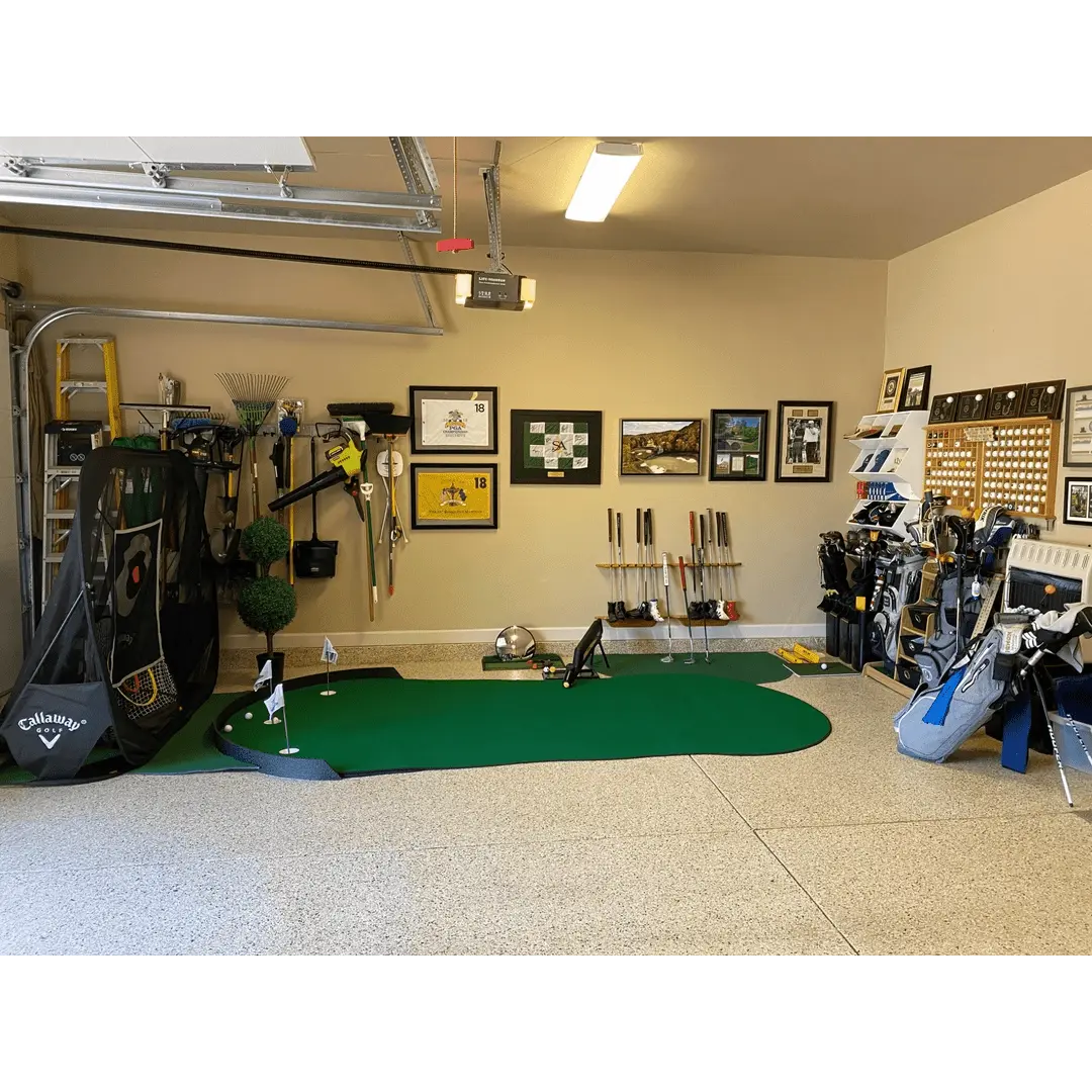 Garage golf setup featuring Big Moss The General Putting Green, golf clubs, a practice net, and golf-themed wall art