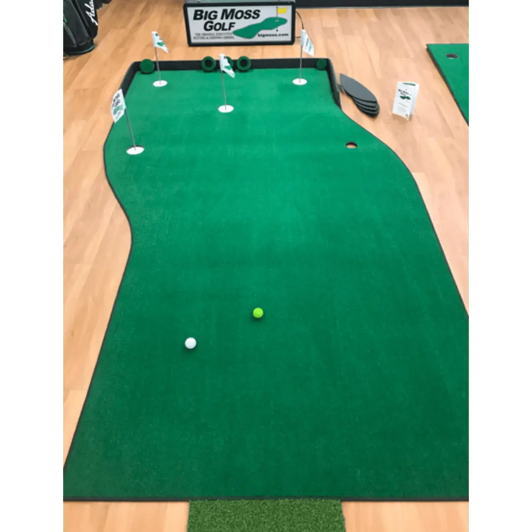 Big Moss The Natural Putting Green with white and yellow balls, flags, and a sign on indoor turf