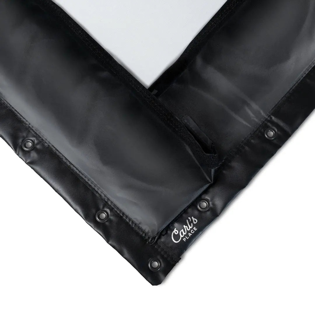 Close-up of golf impact screen with black fabric border, metal grommets, and a branded label in the corner.
