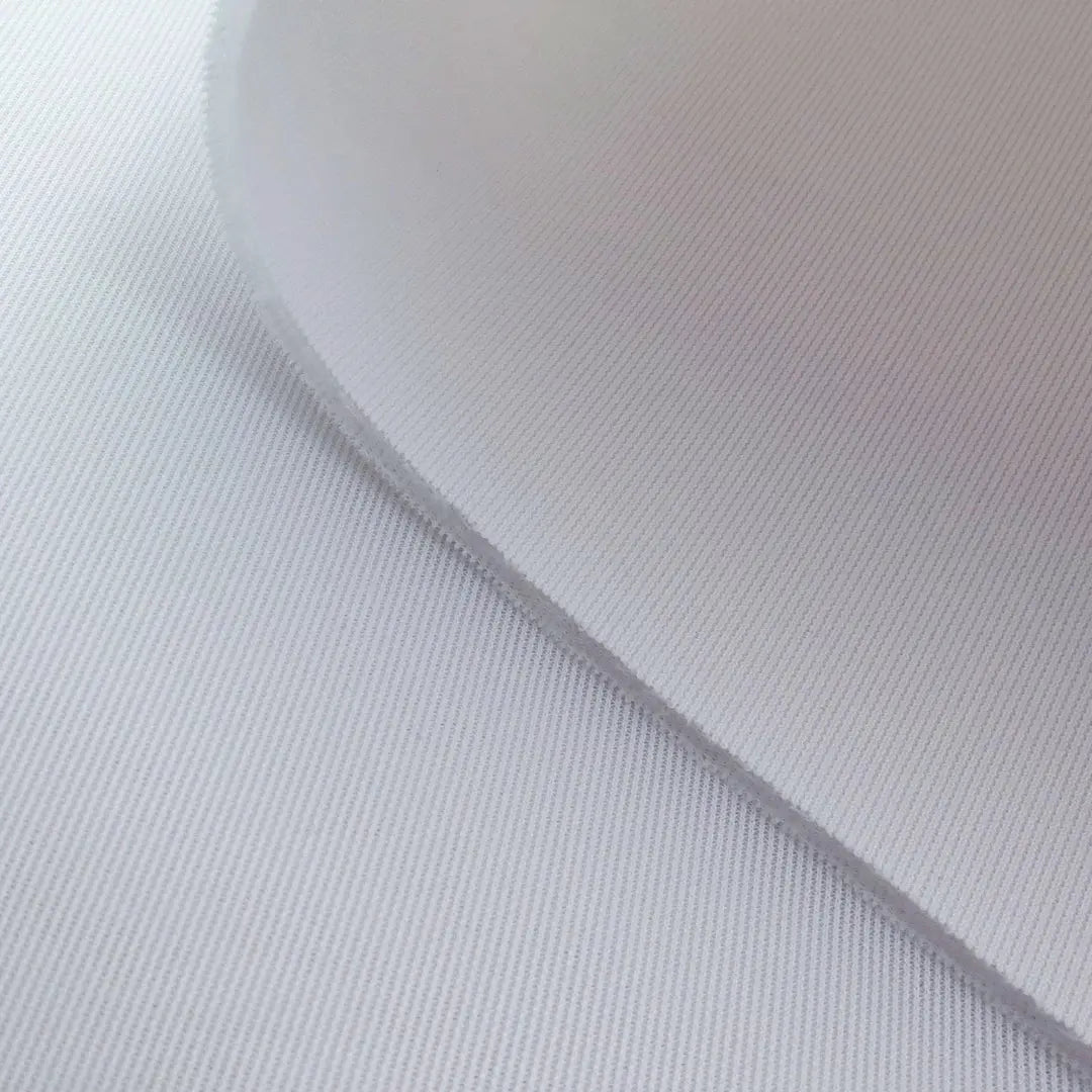 Close-up of white textured fabric on a golf impact screen with a curved edge overlapping another fabric layer