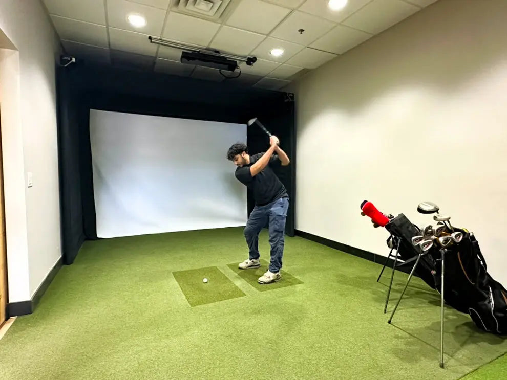A man mid swing in front of the SportScreen Parlour 11 golf simulator enclosure
