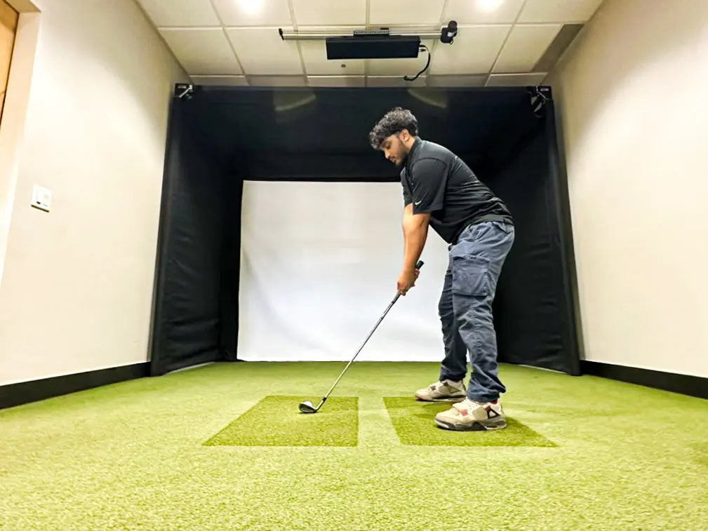 A man practicing his golf swing using the SportScreen Parlour 11 Golf simulator enclosure