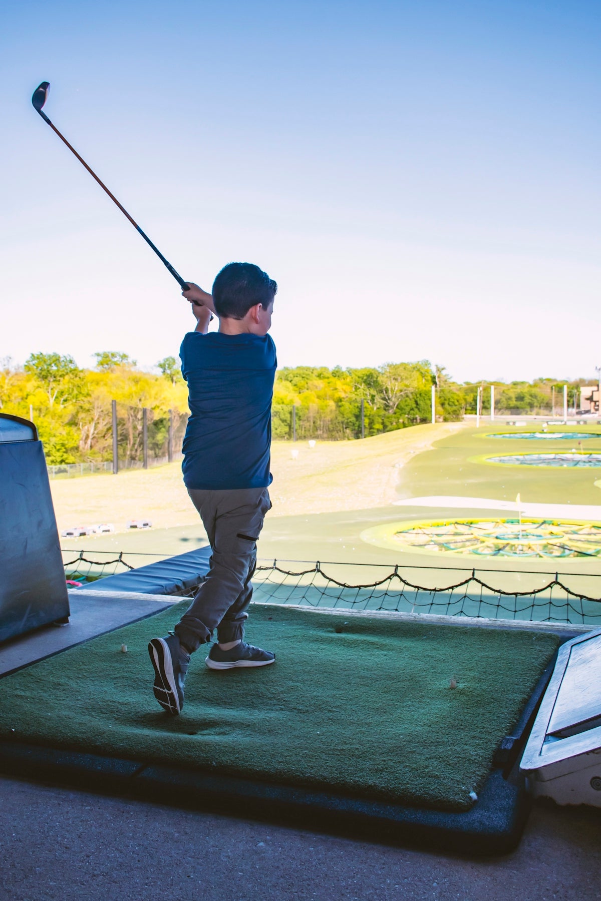 man in blue shirt and black pants holding golf club