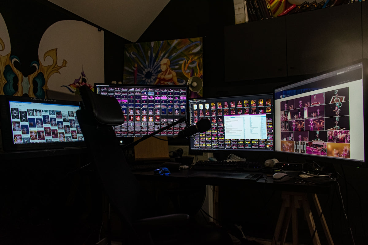 a man sitting in front of three computer monitors