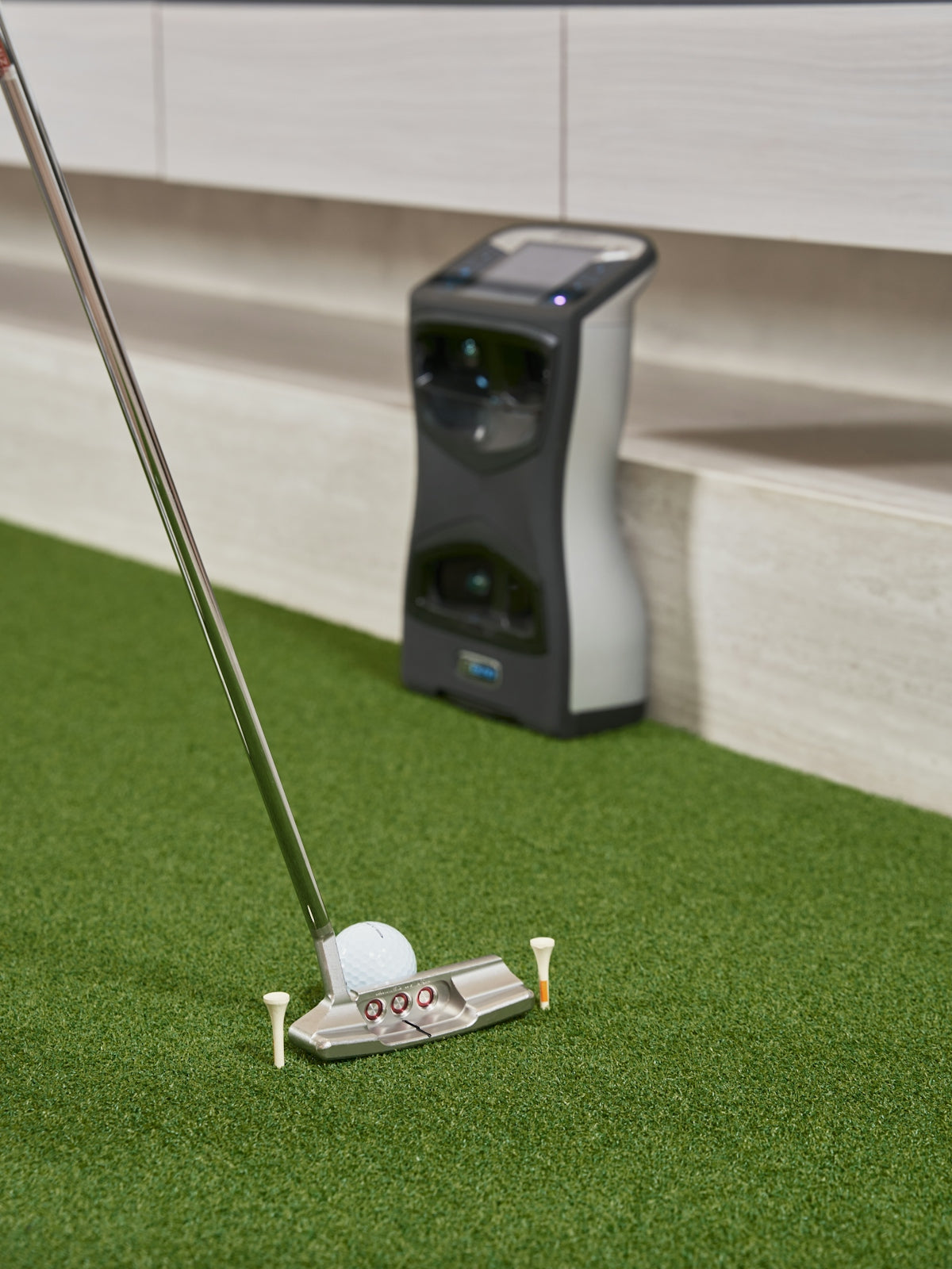 Golf club and ball on artificial turf with device.