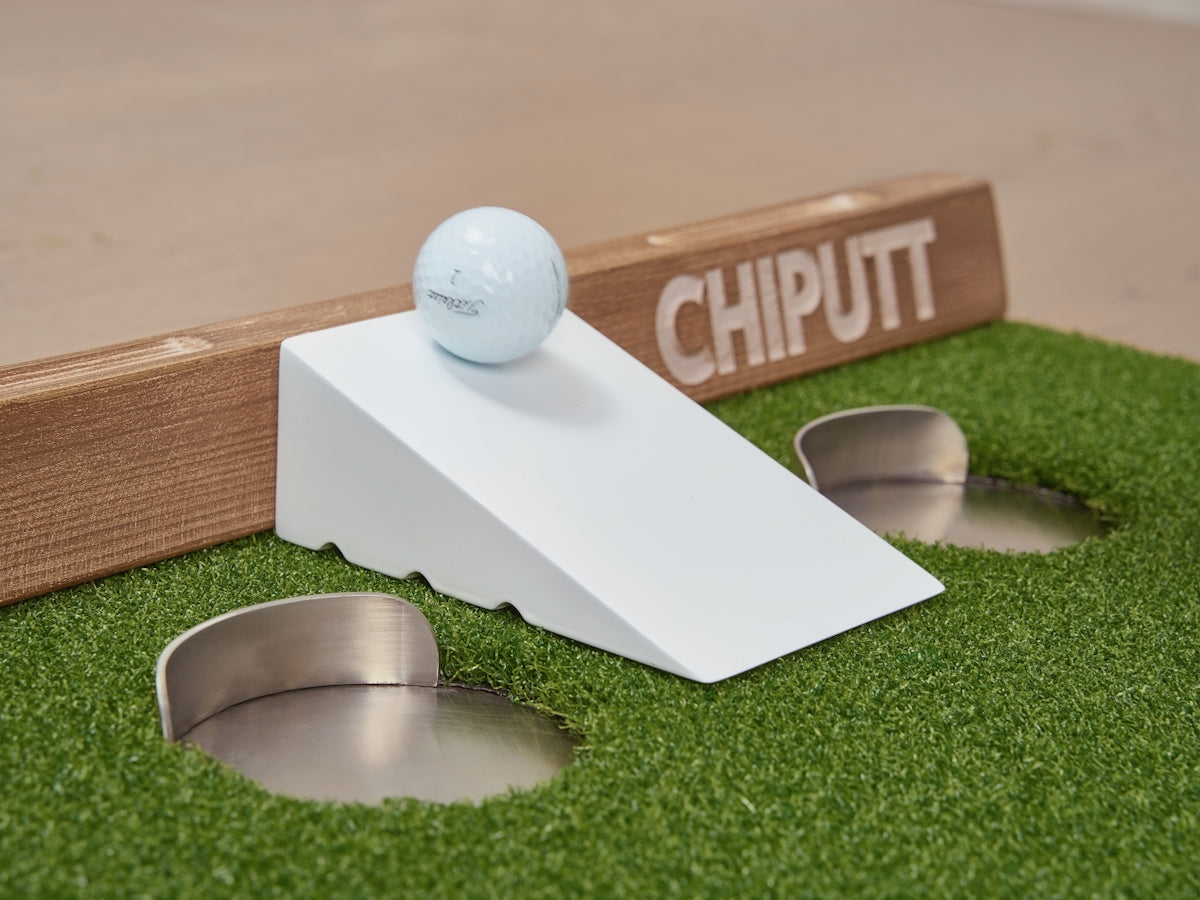 Golf ball on ramp near putting holes