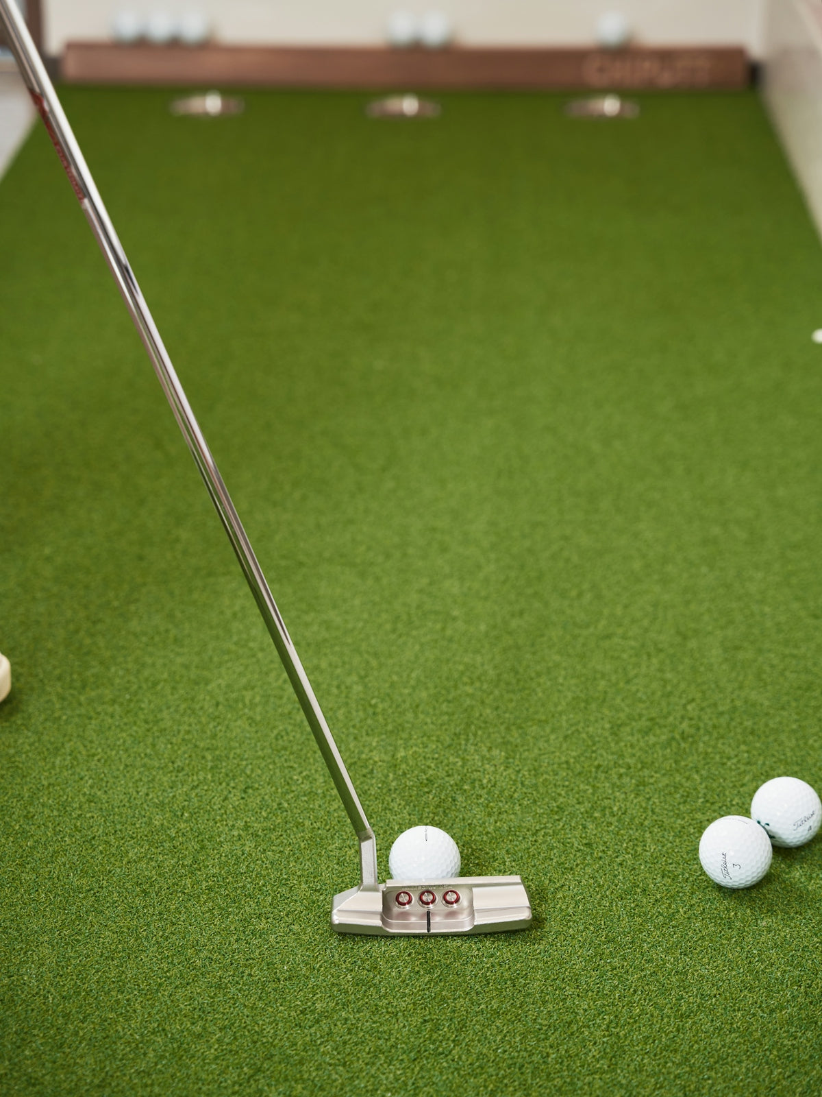 Golf putter and balls on green turf