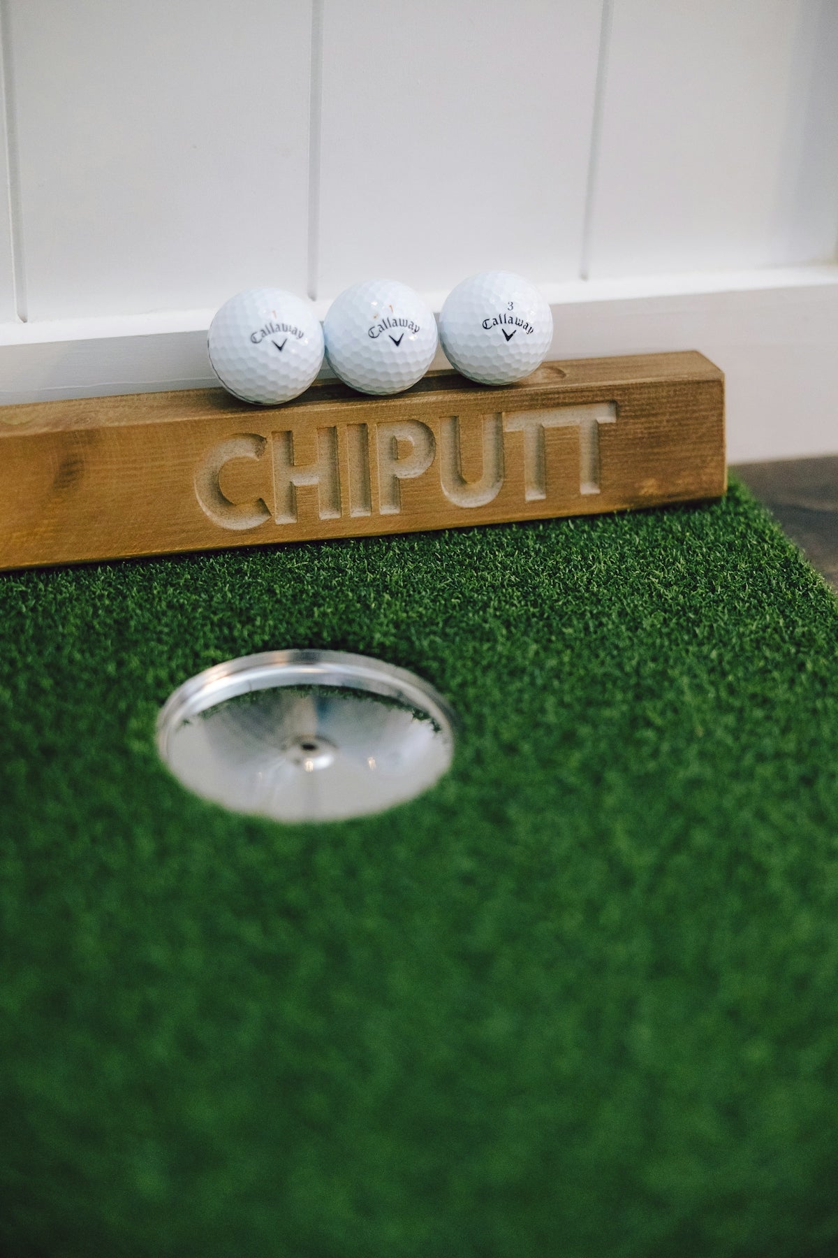 Three golf balls on a putting green near hole.