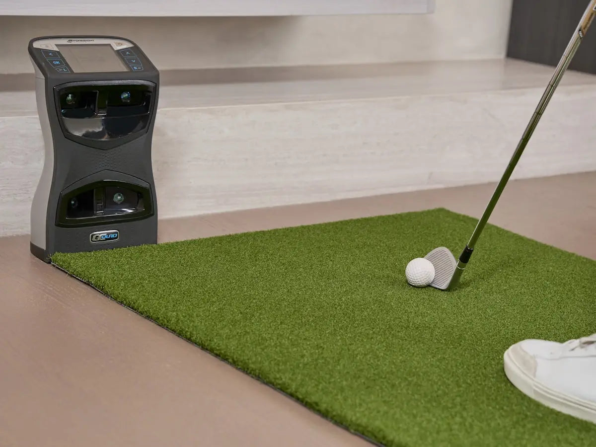 Golf club and ball on putting green with machine.