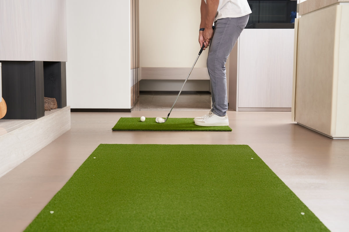 Man practicing golf swing on indoor putting green.