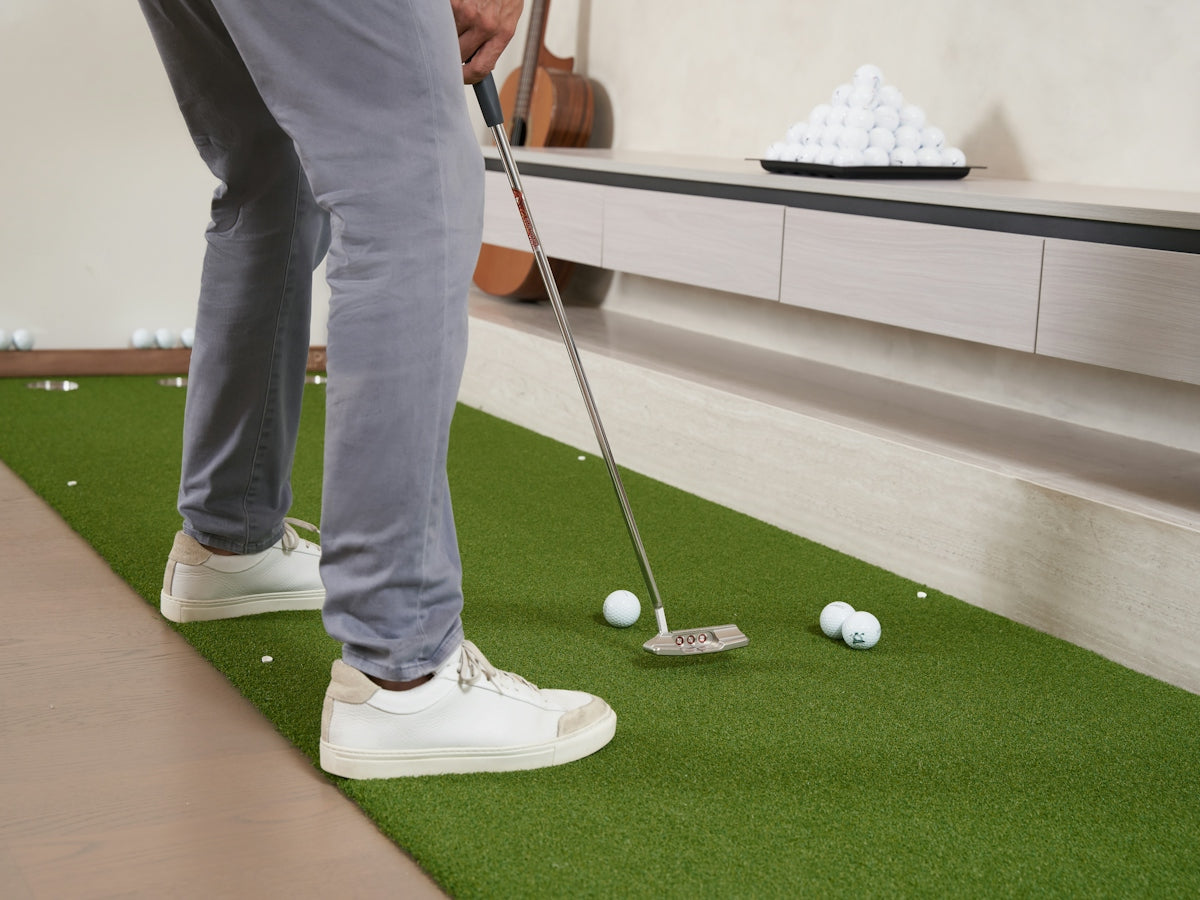 Man playing indoor mini golf with white balls