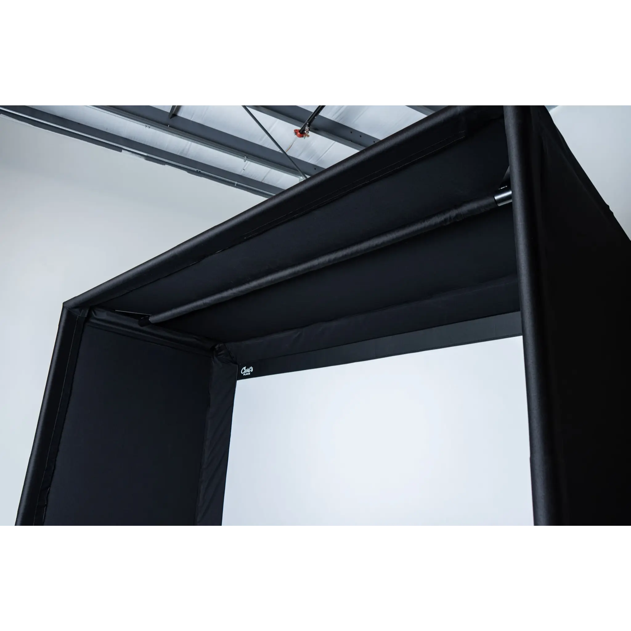 A close-up view of a black golf simulator enclosure featuring a sturdy frame and a white projection screen. The interior is spacious and designed for immersive indoor golfing experiences, suitable for upscale settings.