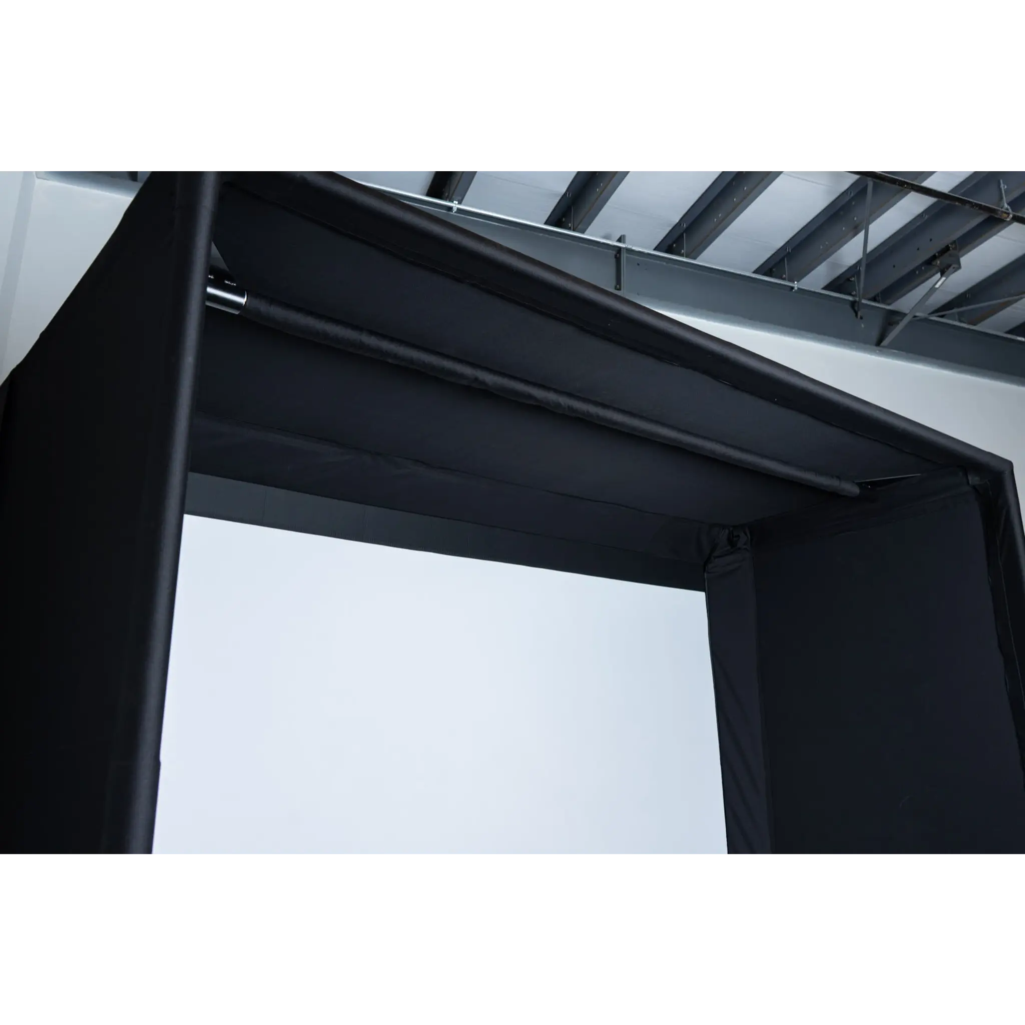 A close-up view of a black golf simulator enclosure featuring a sturdy top frame and a smooth, fabric surface. The setup is designed to create an immersive indoor golfing experience, highlighting its professional-grade construction.