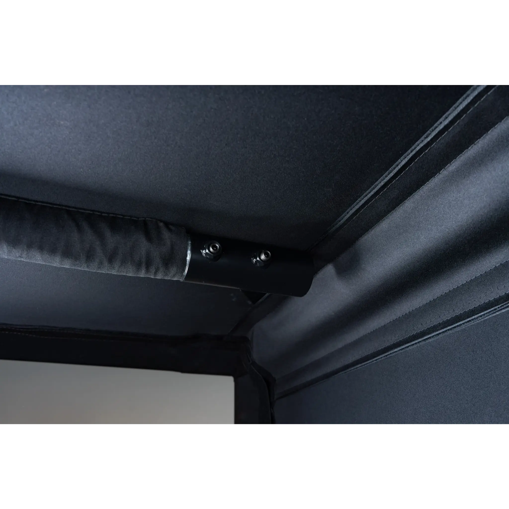 Close-up of a black fabric corner of a golf simulator enclosure, featuring a sturdy support rod with two black screws. The interior fabric has a smooth texture, contributing to a professional and immersive golf experience.